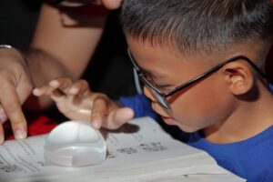 a boy using a dome magnifier to read a book.